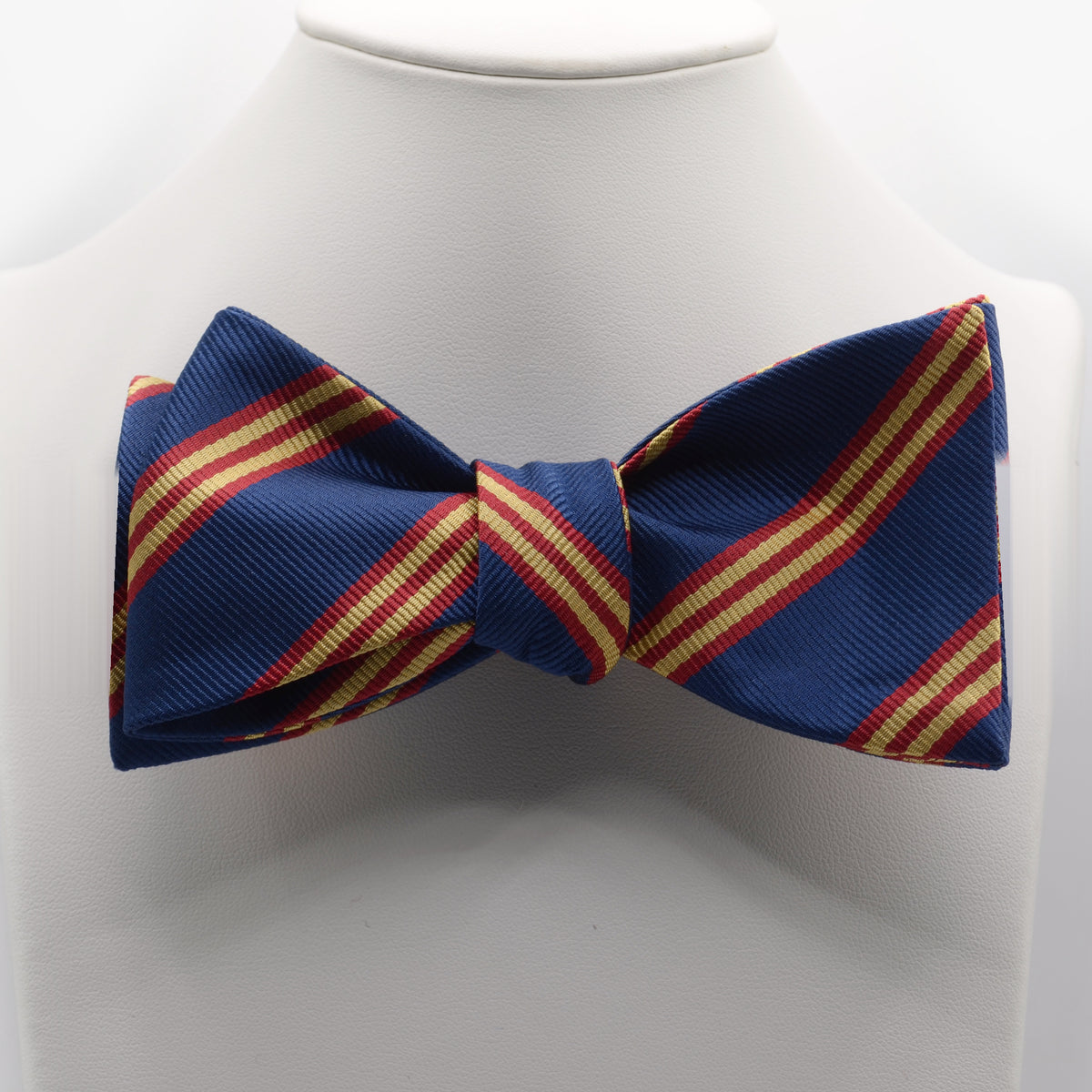 Navy Red and Gold Stripe Bow Tie shown on a white display stand