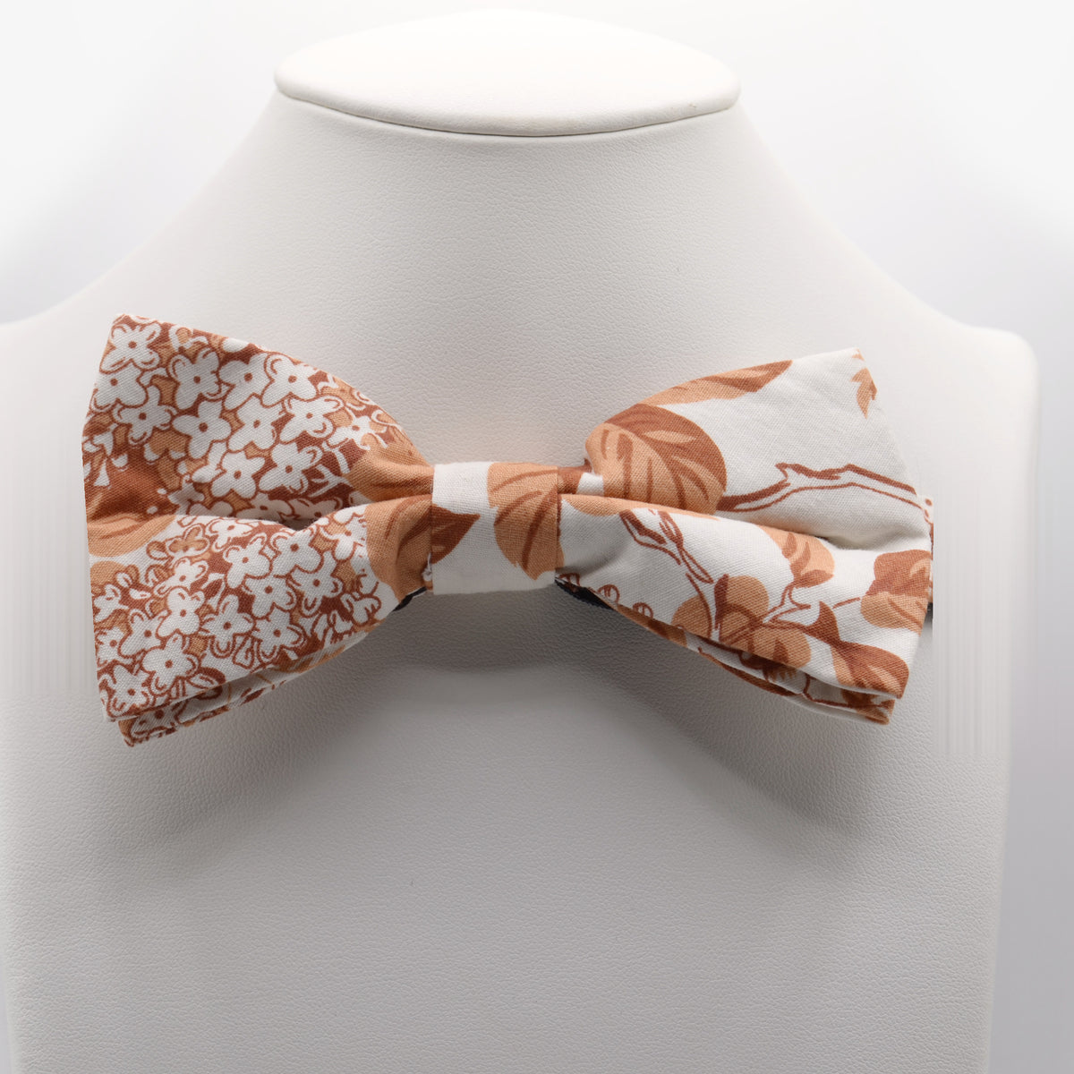 Orange and Cream Floral Bow Tie shown on a white display stand