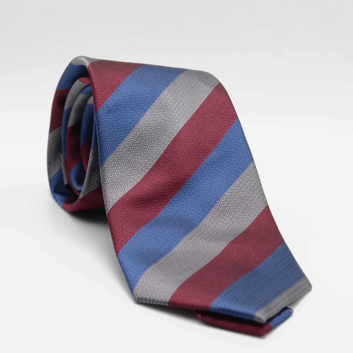 Red Blue and Gray Stripe Necktie rolled on a light background