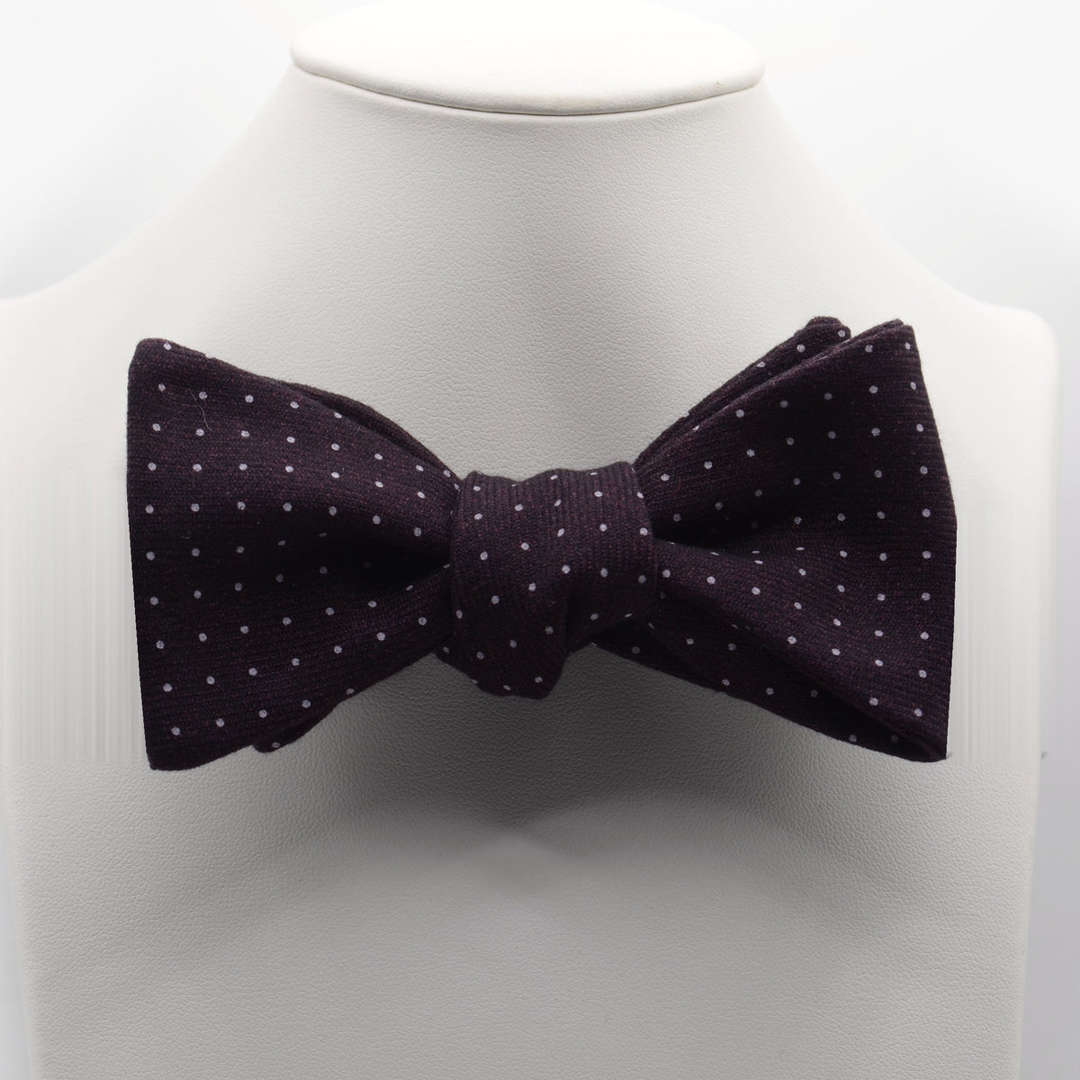 Dark Plum Polka Dot Bow Tie shown on a white display stand