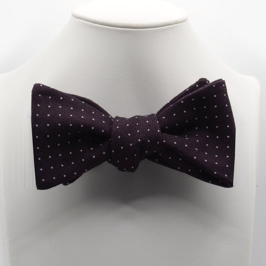 Dark Plum Polka Dot Bow Tie shown on a white display stand