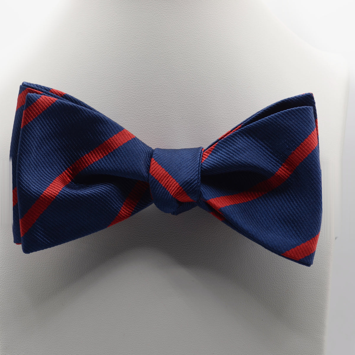 Navy and Red Stripe Bow Tie shown on a white display stand