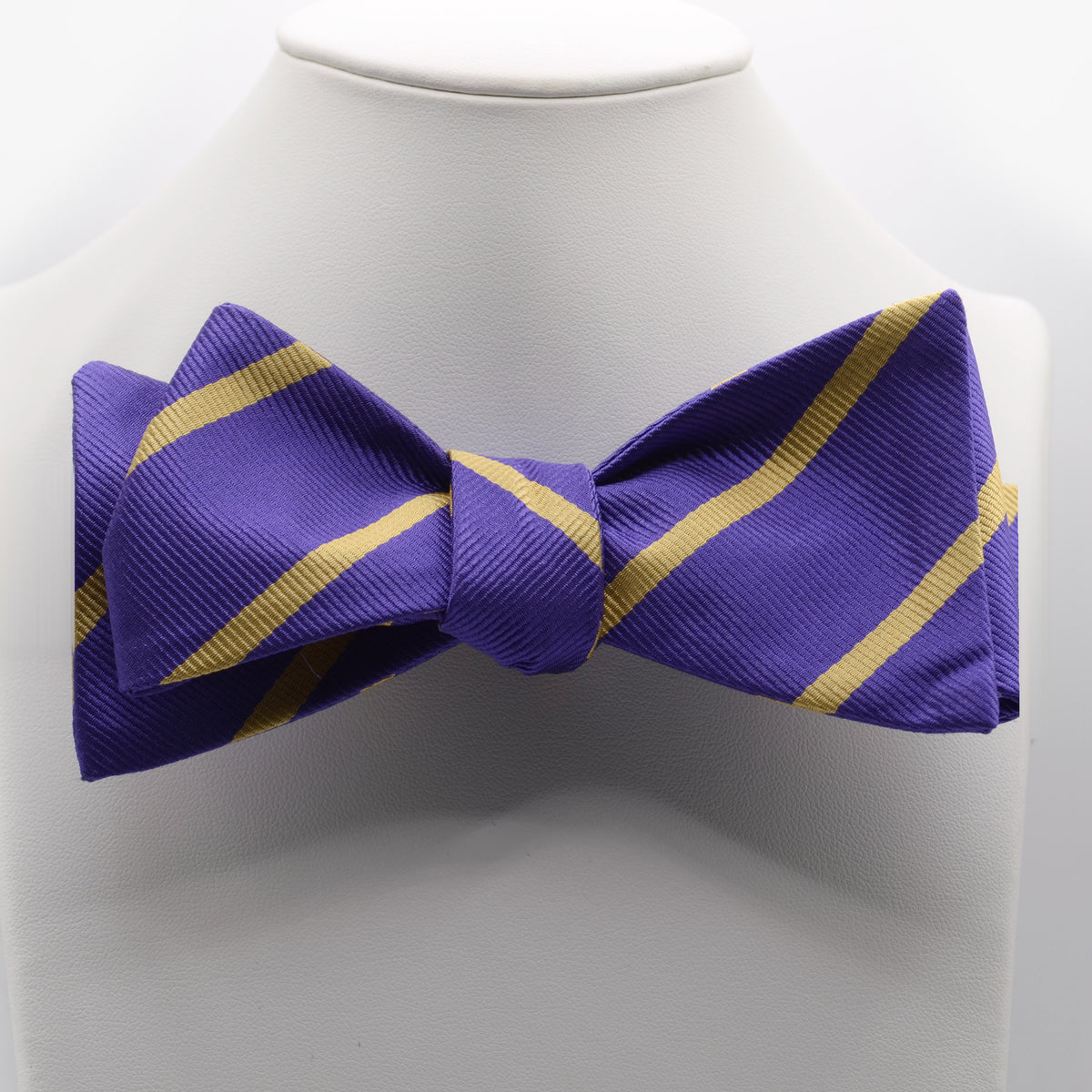 Purple and Gold Stripe Bow Tie shown on a white display stand